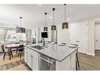 Open-concept kitchen with granite island, stainless dishwasher, and pendant lights leading to the living area at 21893 E Tufts Cir, Aurora, CO 80015