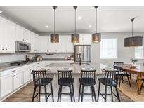 Bright kitchen boasts white cabinets, stainless appliances, granite counters, and a large island with seating at 21893 E Tufts Cir, Aurora, CO 80015