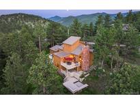 Stunning mountain home featuring multi-tiered decks and an elegant stone chimney surrounded by lush evergreen trees at 207 Kelly E Rd, Boulder, CO 80302
