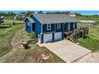 Bright blue exterior view of home, featuring an attached two-car garage and spacious driveway at 36023 Winchester Rd, Elizabeth, CO 80107