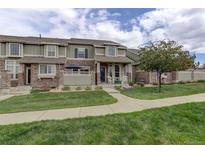 Charming townhome with stone accents, a well-manicured lawn, and a welcoming front porch with rocking chairs at 4784 Raven Run, Broomfield, CO 80023