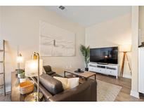 Living room with comfortable leather seating, a decorative rug, and a big screen TV at 5677 S Park Pl # C208, Englewood, CO 80111