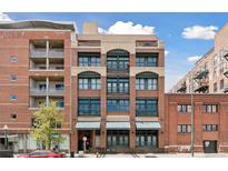 A brick multi-story building with green-trimmed windows, and small balconies outside some windows at 2245 Blake St # C, Denver, CO 80205