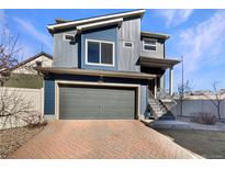 Modern two-story home featuring blue siding, gray garage door, and brick paver driveway at 5470 Danube St, Denver, CO 80249