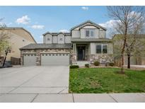 Charming two-story home featuring stone accents, a three-car garage, and a well-manicured lawn at 60 Stewart Way, Erie, CO 80516