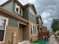 Two-story townhome featuring brown stucco and green siding, situated in a neighborhood under cloudy skies at 12317 W Gould Ave, Littleton, CO 80127