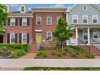 Brick townhome featuring a vibrant green door and landscaped front yard at 8851 E 33Rd Ave, Denver, CO 80238