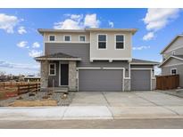 Modern two-story home with a neutral gray exterior, a two-car garage, and stone accents at 170 Lark Sparrow Way, Bennett, CO 80102