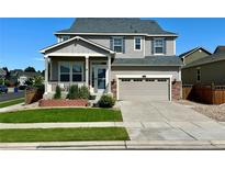 Charming two-story home featuring a landscaped front yard, covered porch, and attached two-car garage at 15446 Coopers Hawk Way, Parker, CO 80134