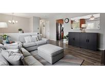 Bright living room featuring modern gray sofa, ottoman and hardwood floors at 12235 Garfield Pl, Thornton, CO 80241