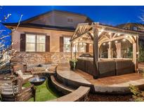 Inviting backyard patio featuring a cozy seating area, fire pit, and pergola with string lights, perfect for outdoor gatherings at 7743 S Quantock Way, Aurora, CO 80016