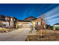 Charming two-story home with a well-manicured lawn and a two-car garage, showcasing its appealing curb appeal at twilight at 7743 S Quantock Way, Aurora, CO 80016