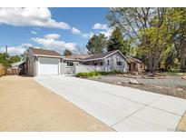 Charming gray home with an attached garage, a long driveway, and a front yard with mature trees at 4500 Zephyr St, Wheat Ridge, CO 80033