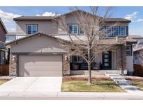 Charming two-story home featuring a two-car garage, covered porch with stone accents, and well-manicured lawn at 11025 Watermark St, Parker, CO 80134
