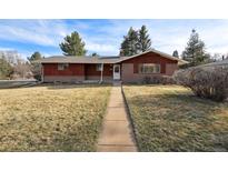Charming home featuring a brick facade, red accents, and a well-maintained front yard with mature trees at 5200 W Ontario Ave, Littleton, CO 80128
