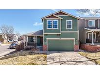 Two-story home with a two-car garage, a covered porch, green siding and brick accents and well-kept lawn at 9811 Gatesbury Cir, Highlands Ranch, CO 80126