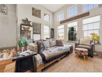 Bright living room featuring high ceilings, large windows, and stylish furniture with a beautiful southwest design throw at 8872 E 47Th Ave, Denver, CO 80238