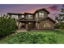 Inviting home featuring stone accents, a well-manicured lawn, and lush greenery at 12161 S Leaning Pine Ct, Parker, CO 80134