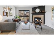 Cozy living room features a fireplace, gray sofa, glass top coffee table, and sliding door to a deck at 10293 E Peakview Ave # F101, Englewood, CO 80111