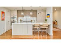 Modern kitchen with a large island, seating, stainless steel appliances, and pendant lighting at 1590 Little Raven St # 702, Denver, CO 80202