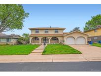 Inviting two-story home with a charming facade, arched entryway, lush lawn, and a two-car garage at 7700 E Oxford Ave, Denver, CO 80237