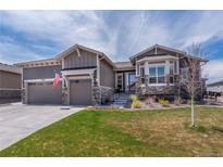 Charming home features a two-car garage, stone accents, and a well-manicured lawn at 8463 S Quemoy Ct, Aurora, CO 80016