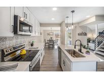 Bright kitchen boasts white cabinets, quartz counters, stainless appliances, and stylish backsplash at 909 Reynolds Farm Ln # C2, Longmont, CO 80503