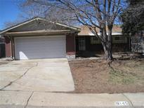 Charming single-story home with a two-car garage and brick accents, complemented by mature trees in the front yard at 8145 Pennsylvania St, Denver, CO 80229