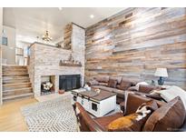 Inviting living room with a stone fireplace and rustic wood accent wall, creating a cozy and stylish atmosphere at 200 Primrose Path # 11, Breckenridge, CO 80424