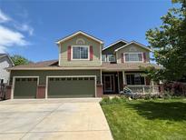 Charming two-story home featuring a three-car garage, front porch, and lush landscaping at 5980 Dunraven Ct, Golden, CO 80403