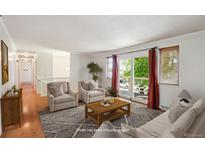 Staged living room featuring hardwood floors, white walls, large windows and stylish, neutral furniture at 1073 Xenon St, Golden, CO 80401