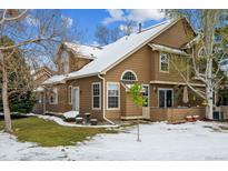 Charming two-story home features a side yard with mature trees and partial snow cover in a cozy neighborhood at 10654 W Dumbarton Cir # A, Littleton, CO 80127