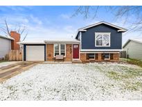 Charming split-level home featuring brick and blue siding, a red front door, and a well-manicured lawn at 4512 S Yank St, Morrison, CO 80465