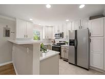 Bright kitchen with stainless steel appliances, white cabinets, tile backsplash, and neutral countertops at 1705 W Stoll Pl, Denver, CO 80221