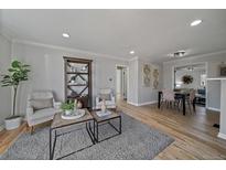 Bright living room boasts hardwood floors, modern decor, and seamless flow to dining area for easy living at 1705 W Stoll Pl, Denver, CO 80221
