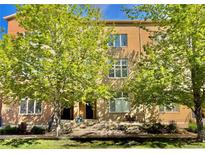 Inviting brick townhome featuring a well-maintained lawn and mature trees providing shade at 7525 E 1St Pl # 1010, Denver, CO 80230