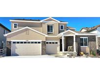 Beautiful tan two-story home with a spacious three-car garage and charming brick accents at 7195 S Yantley Way, Aurora, CO 80016