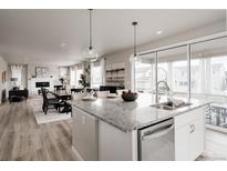 Open-concept kitchen boasts granite counters, stainless appliances, and seamless flow to dining and living areas at 7195 S Yantley Way, Aurora, CO 80016