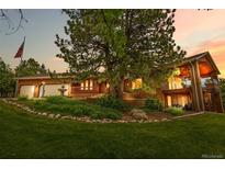 Charming brick home with mature trees, a water feature, and an American flag, creating a welcoming curb appeal at 8662 Kim Ct, Parker, CO 80134