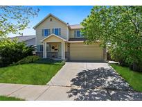 Charming two-story home with a manicured lawn, inviting entrance, and attached two car garage at 11370 Iola St, Commerce City, CO 80640
