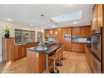 Spacious kitchen features custom wood cabinets, large island with bar seating, and skylight at 38 Hillside Dr, Wheat Ridge, CO 80215