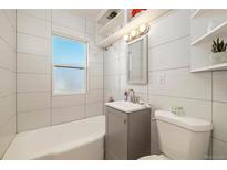 Bright bathroom with modern vanity, tub, and tiled walls at 2570 Jay St, Edgewater, CO 80214