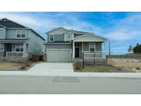Charming gray two-story home featuring a two-car garage and inviting front porch with decorative railing at 467 White Sand Trl, Castle Rock, CO 80104