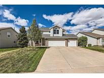 Charming two-story home with a three-car garage and well-manicured lawn on a sunny day at 2369 Bayberry Ln, Castle Rock, CO 80104