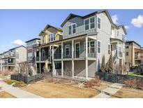 Two-story townhome with gray siding, front porch, and fenced yard at 9085 Delacorte St, Littleton, CO 80129