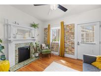 Bright living room features a decorative fireplace, custom book wall design, and a ceiling fan at 2465 W Caithness Pl, Denver, CO 80211