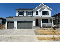 Charming two-story home featuring a two-car garage, white siding, black shutters, and a welcoming front porch at 283 Wooten Ave, Brighton, CO 80601