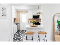 Bright kitchen with black and white tiled floor, white cabinets, and open breakfast bar area with stool seating at 2313 S Race St # A, Denver, CO 80210