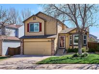 Two-story home with tan siding, brick accents, and a well-maintained lawn at 9652 Cove Creek Dr, Highlands Ranch, CO 80129