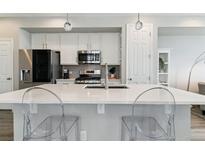 Modern kitchen features white cabinets, stainless steel appliances, and a large center island with seating at 9612 Reunion Pkwy, Commerce City, CO 80022